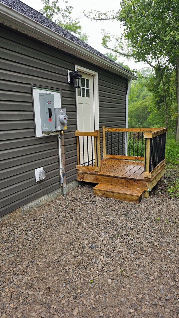 Un bâtiment doté d’une terrasse en bois, d’une porte et de boîtiers électriques.