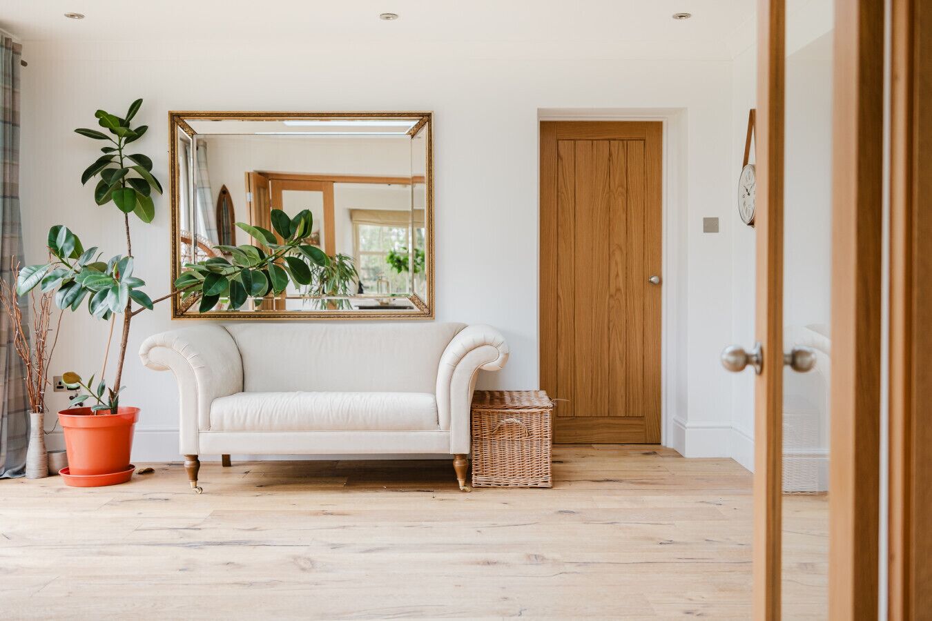 A room with a white sofa, a large mirror, and a wooden door.