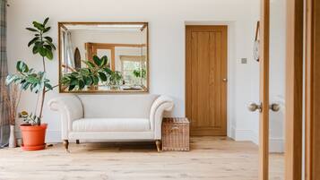 A room with a white sofa, a large mirror, and a wooden door.