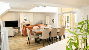 Una sala de estar moderna con un sofá, televisión y comedor con sillas y una mesa.