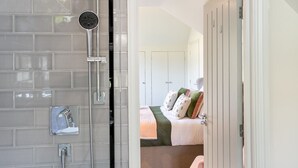 Un baño con cabina de ducha de vidrio, ducha de mano y perchero.