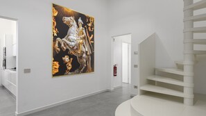 Un interno moderno con un'ampia opera d'arte a parete, una scala e un estintore.