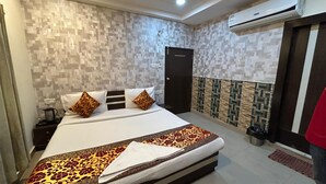 A hotel room with a bed, nightstand, and an air conditioning unit. - 45-room hotel in delightful Varanasi with WiFi, AC. Unwind in comfort (Varanasi)