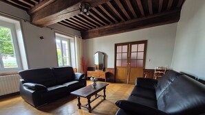 A living room with a wooden herringbone floor, two black leather sofas, a wooden coffee table, and a wooden cabinet. - Charming house in the Charolais countryside overlooking the valley (VIRY)