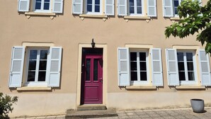 A two-story building with a red door, multiple windows with shutters, and a tiled roof. - Charming house in the Charolais countryside overlooking the valley (VIRY)