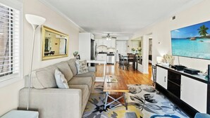 A modern living room with a sofa, coffee table, and a TV on a stand.
