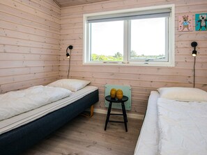 A room with two beds, a window, and a small table with decorative items.