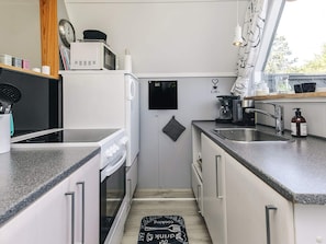 A compact kitchen with a microwave, stove, and coffee maker.
