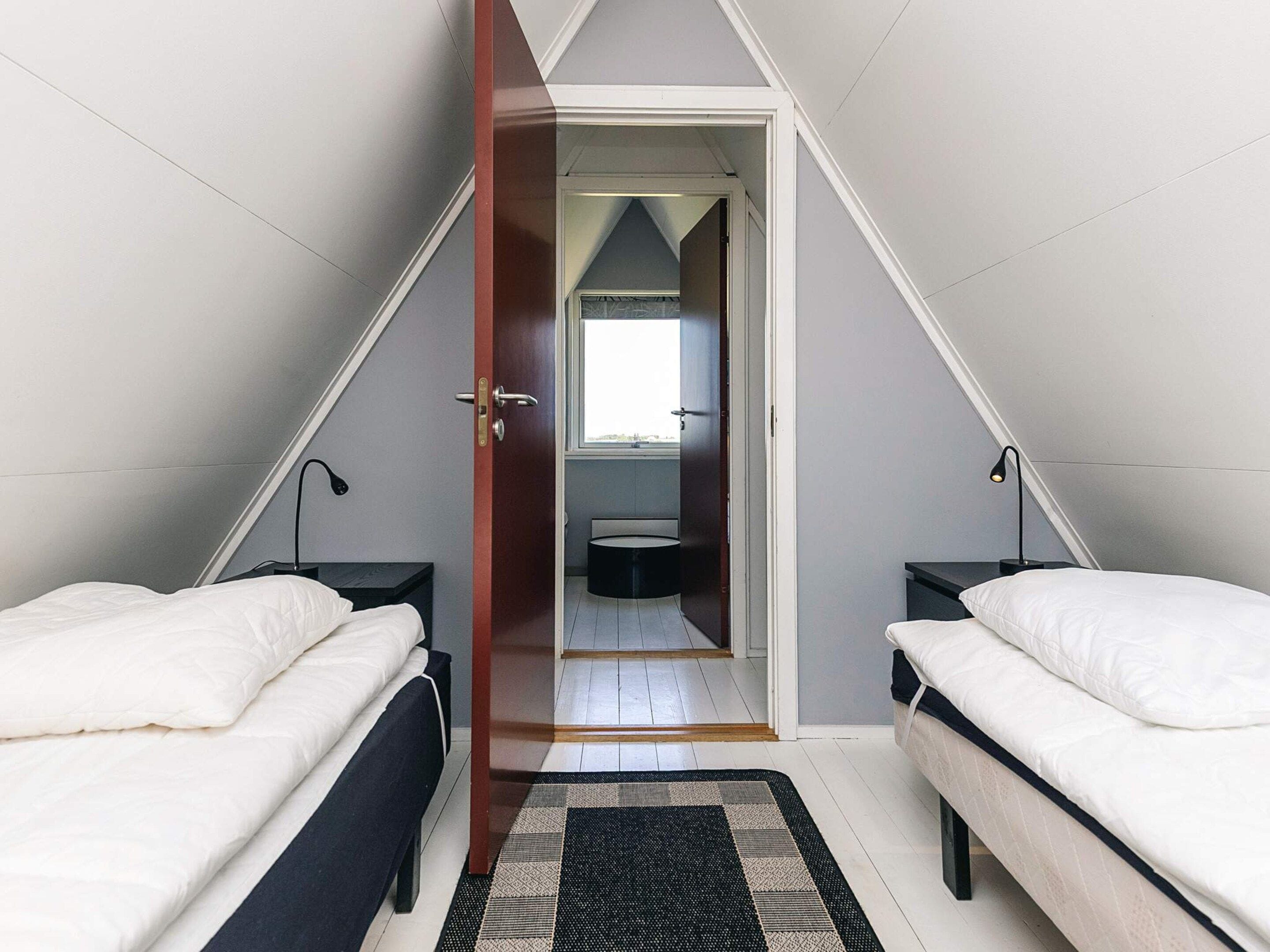 Een slaapkamer met twee bedden, een deur naar een badkamer en uitzicht op buiten.