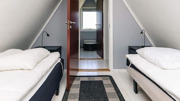 Een slaapkamer met twee bedden, een deur naar een badkamer en uitzicht op buiten.
