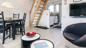 Ein kompakter Wohnbereich mit Essplatz, einer Küche, einer Treppe und einem Fernseher.