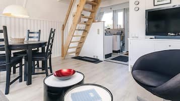 A modern living room with a dining area, a TV, and a staircase leading to an upper level.