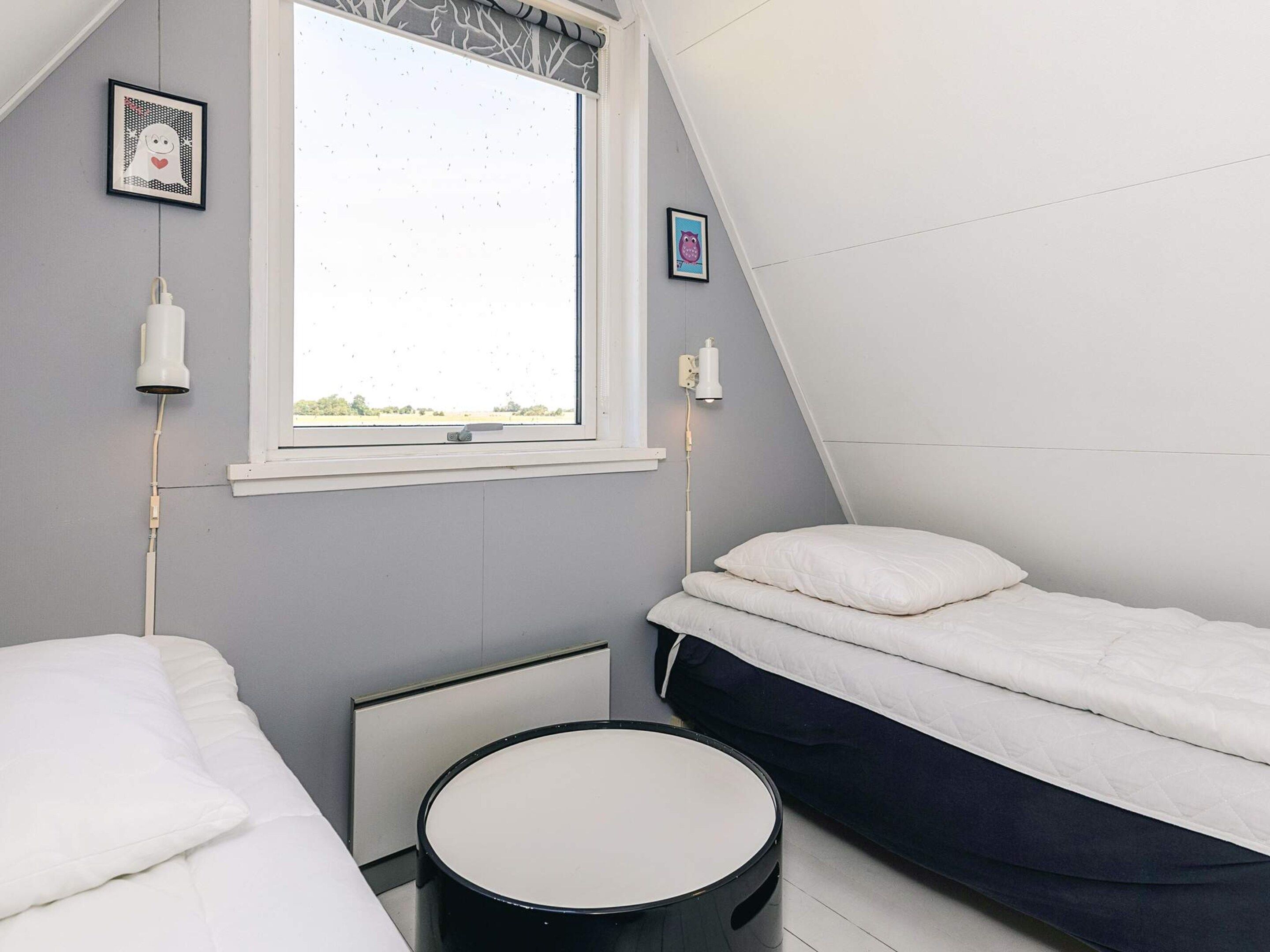 A bedroom with two beds, a window, and a round table.