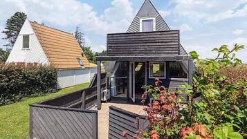 A modern two-story house with a sloped roof, a balcony, and a small attached shed.