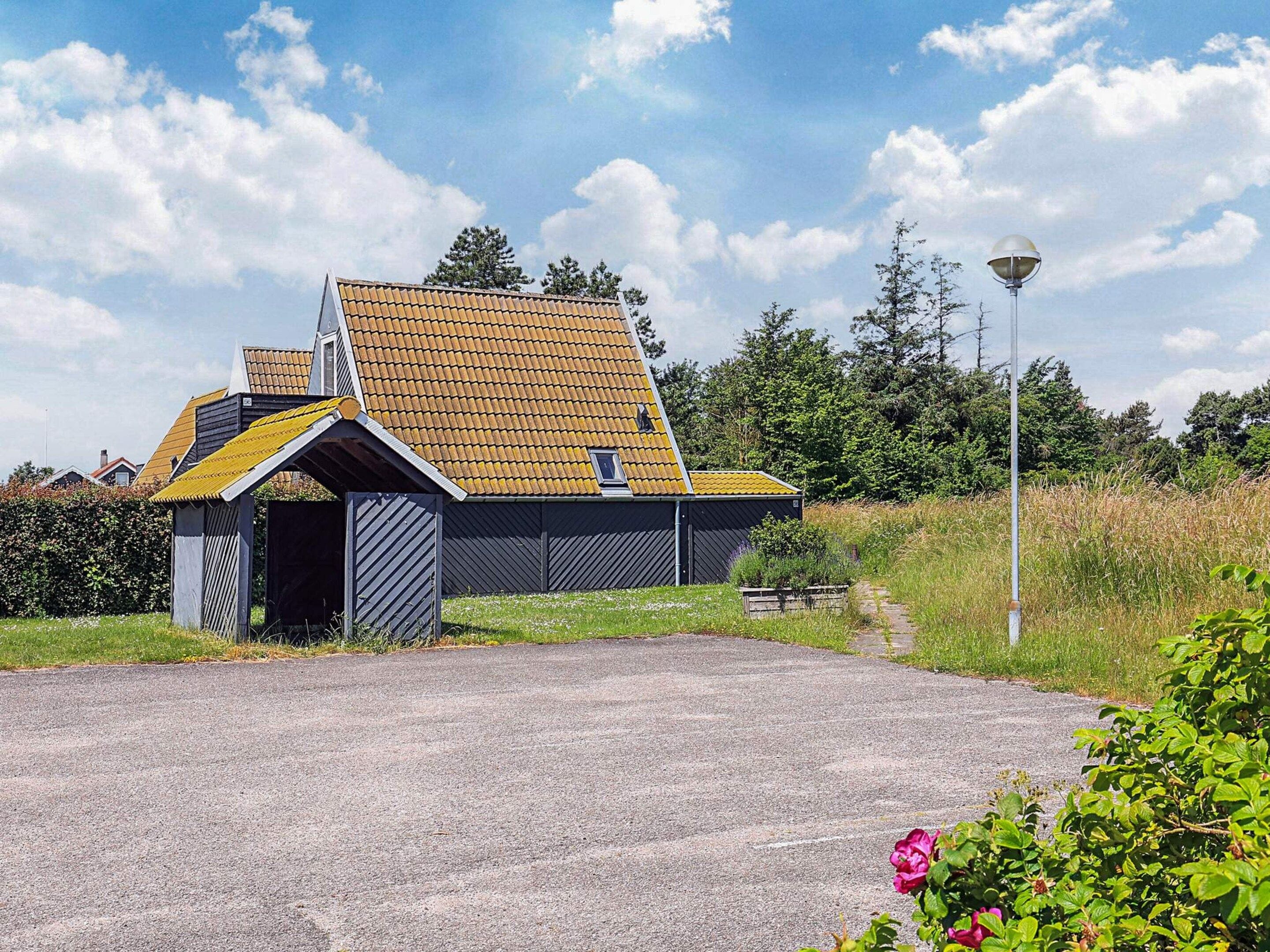 A modern building with a sloped roof, a small attached structure, and a paved driveway.