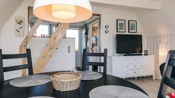 A dining area with a black table, grey placemats, a woven basket, and a white ceiling with a large light fixture.