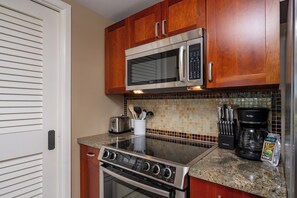 A kitchen with wooden cabinets, a stainless steel microwave, a gas stove, and a coffee maker.