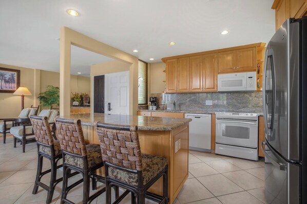 A kitchen with wooden cabinets, a stainless steel refrigerator, a microwave, and a built-in oven.