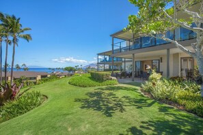 Une maison moderne à deux étages, dotée d’un patio couvert, d’une pelouse verdoyante et offrant une vue sur l’océan.