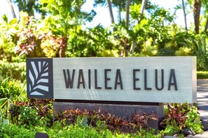 A sign with the text 'WAILEA ELUA' surrounded by greenery. - Wailea Elua | Ocean View 4 BR, Sleeps 12 | Car Incl. w/ 6+ Nights | WEV ML-1137 by KBM (Wailea)