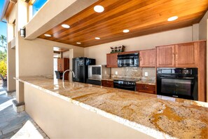 A modern kitchen with granite countertops, stainless steel appliances, and wooden cabinetry.