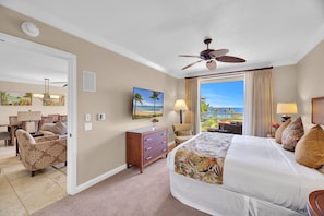 A hotel room with a bed, a desk, a chair, a television, and a view of the ocean.