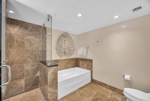 A modern bathroom with a bathtub, shower, and toilet.