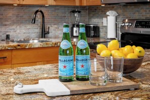 Un comptoir de cuisine avec des bouteilles d’eau Pellegrino, un bol de citrons et des verres.