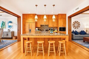 Une cuisine moderne avec des meubles en bois, un plan de travail en granit et un îlot central doté de tabourets.