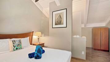 Une chambre d’hôtel avec un lit, une table de chevet, une lampe, une armoire et un tableau encadré au mur.