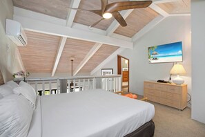 A bedroom with a bed, a dresser, a ceiling fan, a painting, and a balcony.
