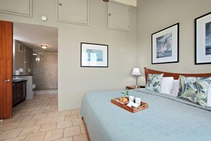 A hotel room with a bed, a tray with breakfast items, a bathroom, and framed pictures on the wall. - Papakea | Ocean View 6 BR, Sleeps 16 | Car Incl. w/ 6+ Nights | PKC ML-1169 by KBM (Lahaina)