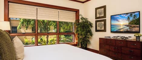 Quarto com uma janela grande, cama, cômoda e televisão.