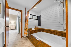 Un baño con bañera, ducha y piso de baldosas.