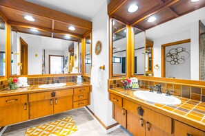 A bathroom with wooden cabinetry, a large mirror, and a tiled backsplash.