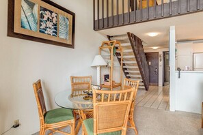 A dining area with wicker furniture, a glass table, and a staircase leading to an upper level. - Napili Point | Oceanfront 4 BR, Sleeps 10 | Car Incl. w/ 6+ Nights | NAP ML-1175 by KBM (Lahaina)