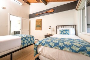 A bedroom with two beds, a nightstand, a lamp, and a framed picture on the wall.