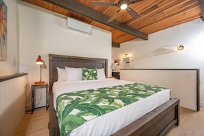 A bedroom with a bed, a ceiling fan, a wall-mounted air conditioner, a bedside lamp, and a nightstand. - Napili Point | Oceanfront 4 BR, Sleeps 10 | Car Incl. w/ 6+ Nights | NAP ML-1175 by KBM (Lahaina)