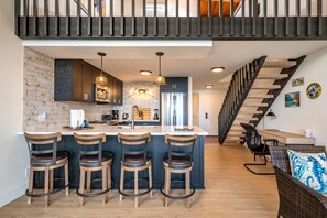 Une cuisine moderne dotée d’un îlot central, de tabourets de bar et d’un escalier menant à un niveau supérieur.