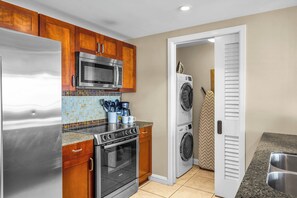 Cocina compacta con refrigerador, microondas, estufa y lavadora.