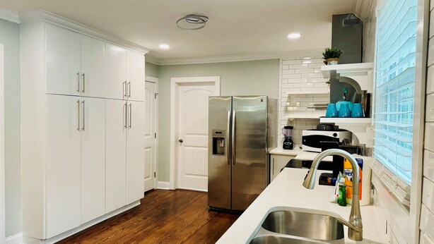A modern kitchen with white cabinetry, a stainless steel refrigerator, a double sink, and a countertop with various appliances. - NEW! 3BR/2BA home in the heart of Spartanburg SC! (Spartanburg)