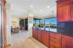 Una cocina con armarios de madera, una isla grande y vista al océano.