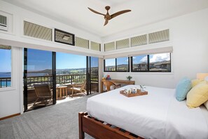 Une chambre avec un grand lit, un bureau, une chaise et un balcon avec vue.