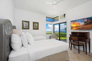 Ein Schlafzimmer mit Bett, Schreibtisch, Stuhl, Deckenventilator und einem großen Fenster mit Aussicht.