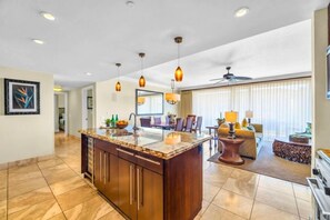 A spacious kitchen with a central island, pendant lighting, and a dining area with a sofa and table.