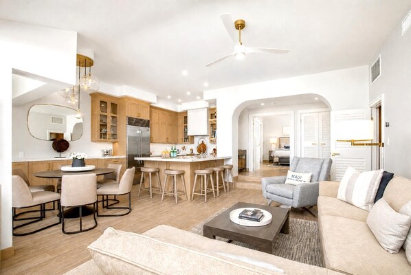 A modern living room with a sofa, coffee table, and a dining area with chairs and a table.