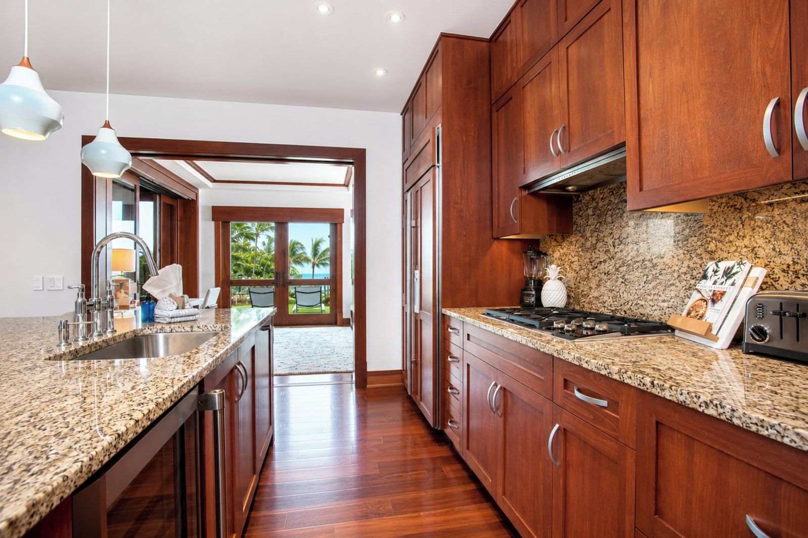 A kitchen with granite countertops, wooden cabinets, a stove, and a view through the door.