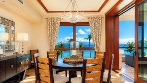 A dining area with a table, chairs, and a view of the ocean.