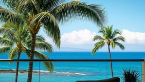 A balcony with a view of the ocean, palm trees, and a chair.