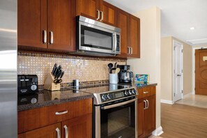 A kitchen with wooden cabinets, a stainless steel microwave, a coffee maker, and a toaster. - 2 Honua Kai Villas | Ocean Front | Sleeps 12 | Free Car w/ 6+ Nights | ML-1239 (Lahaina)